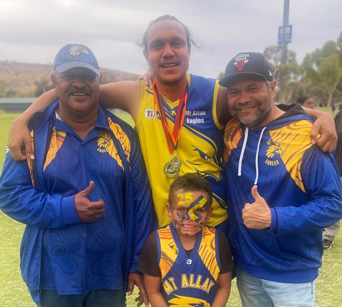 Daniel Stafford (Junior) with his Grand Final medal and his Best on Ground medal. He is with Daniel Stafford (Senior), Vaughn Hampton (Team Leader - Youth Sports and Community Safety – Yuelamu) and young Nakia Stafford. 
