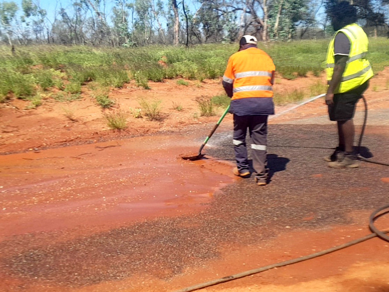 Terry Drover and Bruno Tilmouth clean up the road after the flood in Engawala